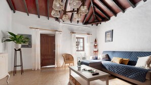 A living room with a sofa, a coffee table, a chair, a potted plant, and a wooden door. - Vacation Home 'Casa Haba' with Sea View, Terrace & Wi-Fi (Sauzal)