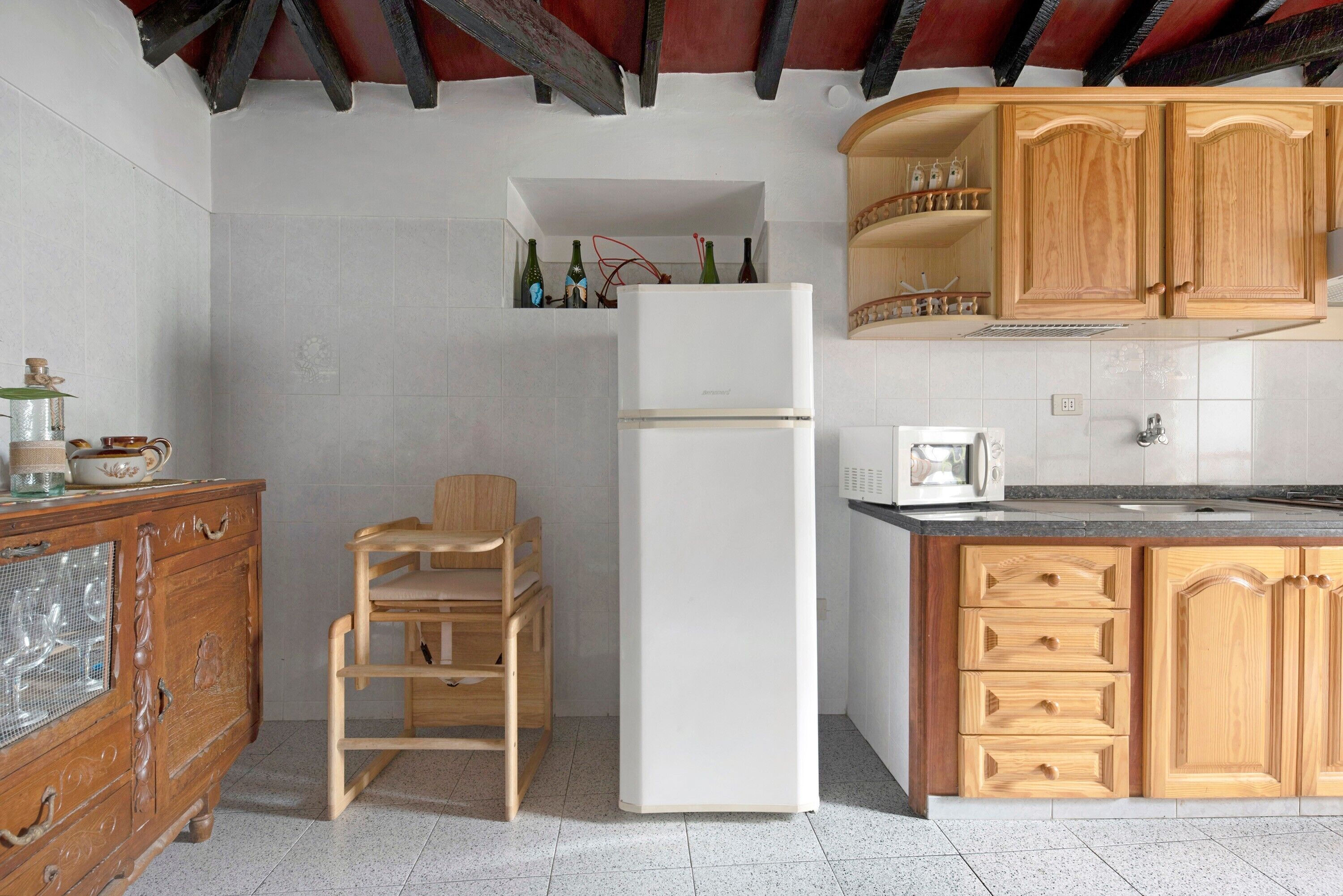 A kitchen with wooden cabinets, a white refrigerator, and a wooden chair.
