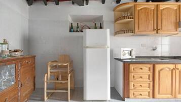 A kitchen with wooden cabinets, a white refrigerator, and a wooden chair.