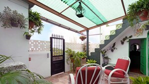 A covered patio area with a white chair and table, potted plants, and a gate. - Vacation Home 'Casa Haba' with Sea View, Terrace & Wi-Fi (Sauzal)
