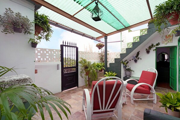 A covered patio area with a white chair and table, potted plants, and a gate. - Vacation Home 'Casa Haba' with Sea View, Terrace & Wi-Fi (Sauzal)