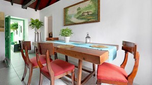 A dining area with a wooden table, red cushioned chairs, a painting on the wall, and potted plants. - Vacation Home 'Casa Haba' with Sea View, Terrace & Wi-Fi (Sauzal)