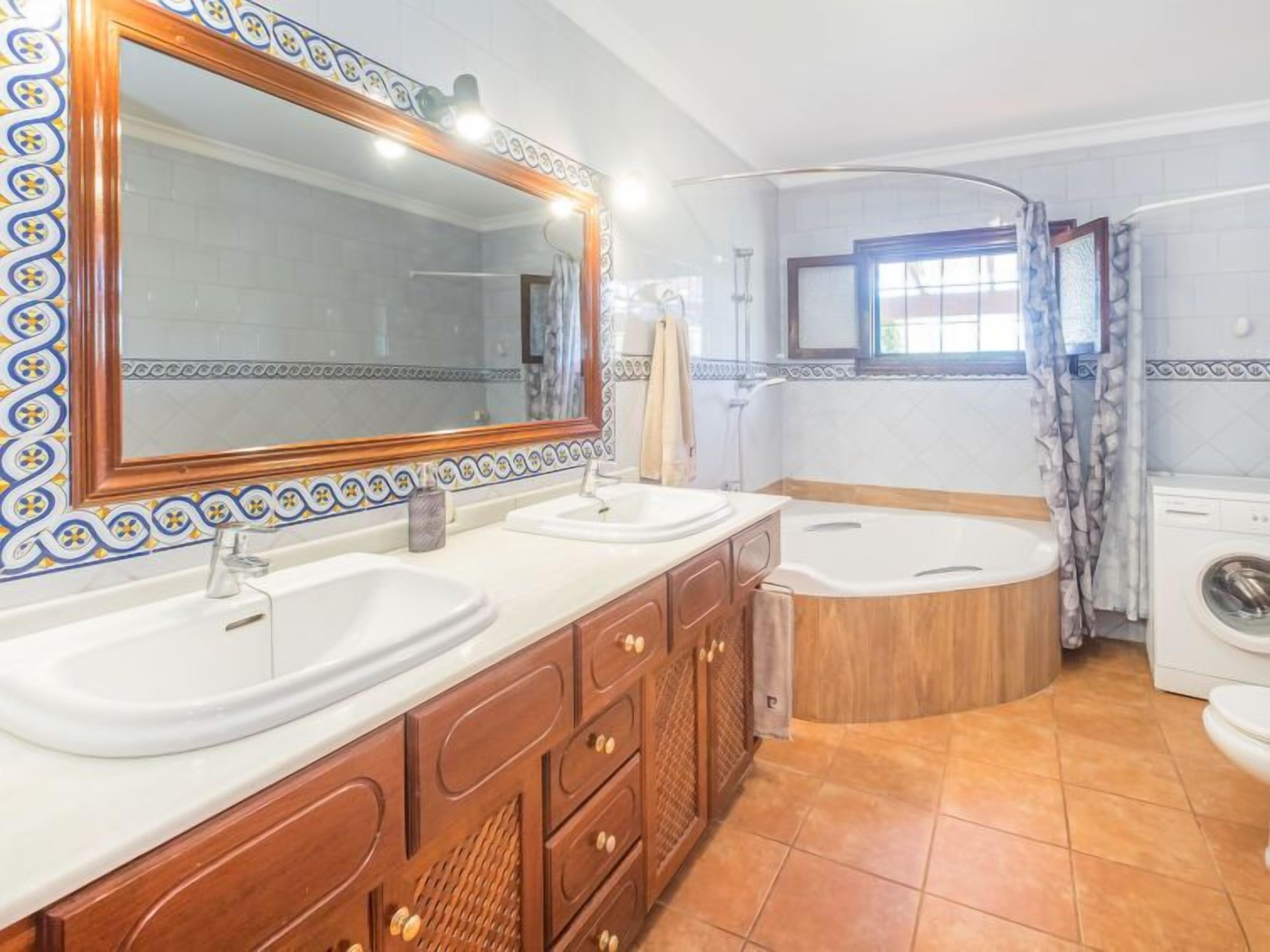 Une salle de bain avec deux lavabos, une baignoire et un lave-linge.