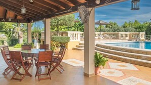 An outdoor patio with a pool, wooden furniture, and a view of the pool area. - Can Cerda by Interhome (Alcúdia)