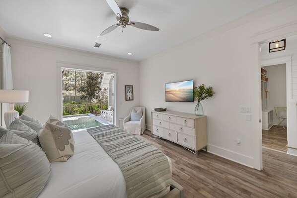 A spacious bedroom with a large bed, a ceiling fan, a TV, and a view of the outdoors. - Outdoor Shower | Private Pool | LSV | Grill (Santa Rosa Beach)