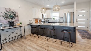 Una cocina moderna con una isla grande, taburetes de bar e iluminación colgante.
