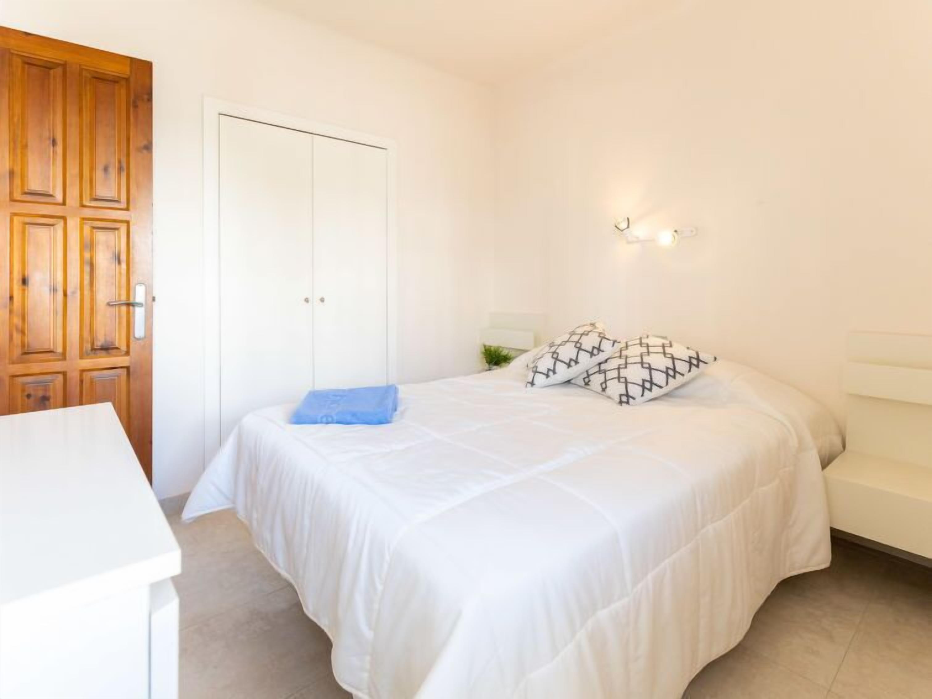 A bedroom with a bed, a desk, and a wardrobe.