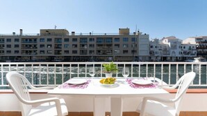 Een terras met een tafel gedekt voor twee, met uitzicht op een waterpartij en gebouwen op de achtergrond.