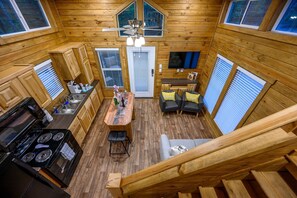 A cozy cabin-style kitchen with wooden walls, a dining area, and a living space.