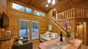 L'intérieur d'un chalet en bois, avec un canapé, une table à manger et un escalier.