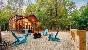 A cabin with a deck, outdoor seating, and a fire pit.