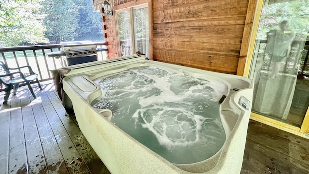 A hot tub on a wooden deck with a view of trees. - Whisper Creek 2 Bedroom Cabin by RedAwning (Townsend)