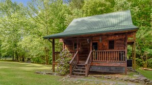 A rustic cabin with a metal roof, wooden porch, and stone steps. - Whisper Creek 2 Bedroom Cabin by RedAwning (Townsend)