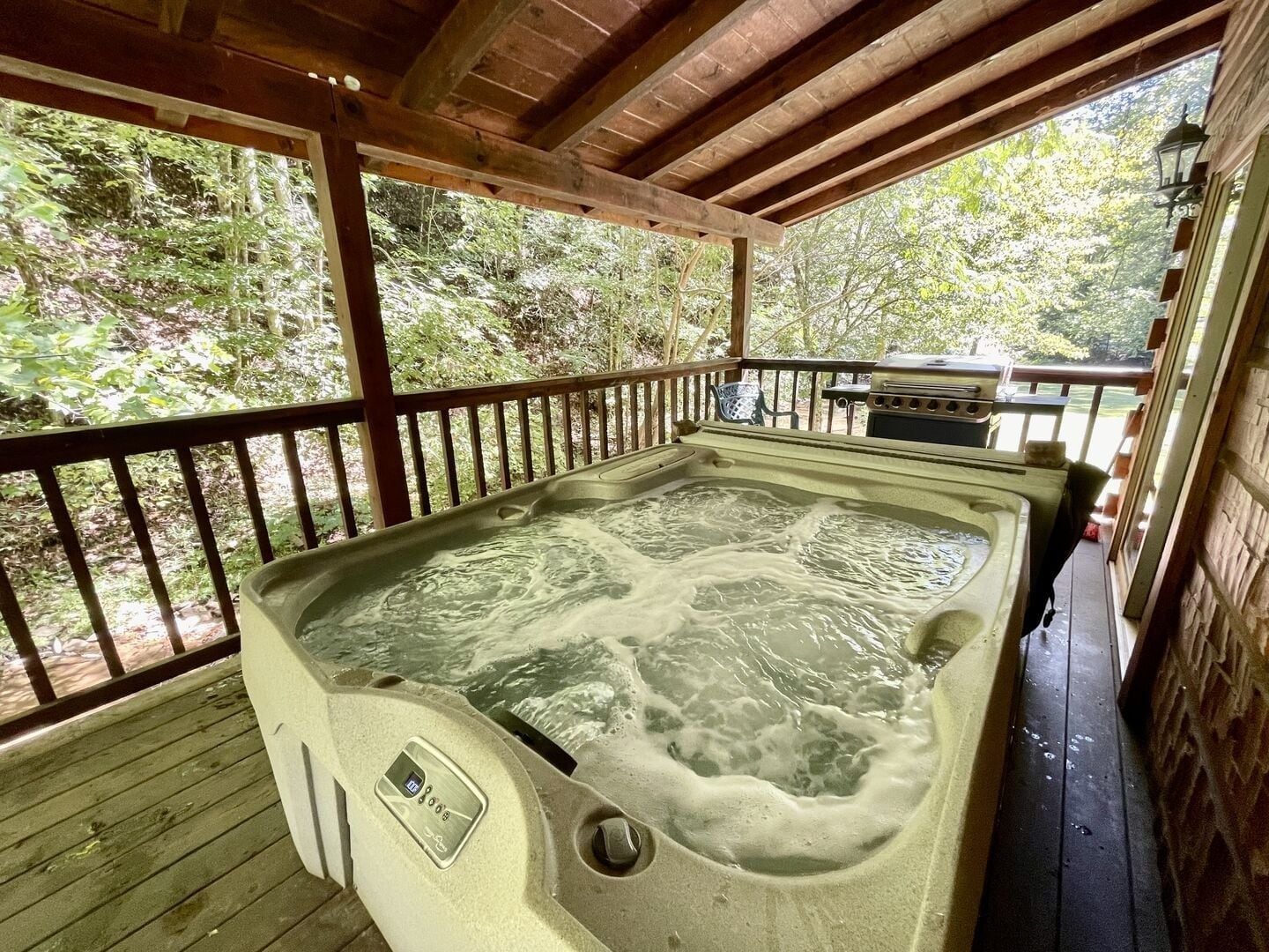 A hot tub on a wooden deck with a view of trees.
