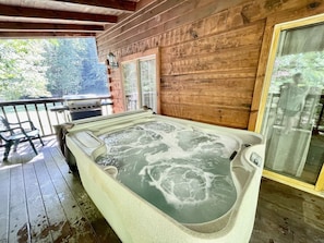Ein Whirlpool auf einer Holzterrasse mit Blick auf Bäume.