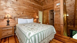 A wooden cabin bedroom with a bed, nightstands, and a window with blinds. - Whisper Creek 2 Bedroom Cabin by RedAwning (Townsend)