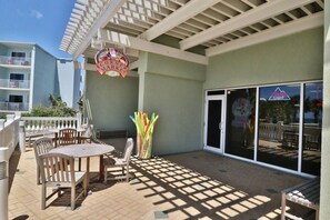 Eine überdachte Terrasse im Freien mit Holztischen und -stühlen, einem Coors Light Schild und dem Coors Light Logo auf den Glastüren.