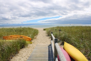 A wooden boardwalk leading to a beach with kayaks and a sailboat in the distance. - Water Access Condo on Cape Cod Bay (2284) (Provincetown)