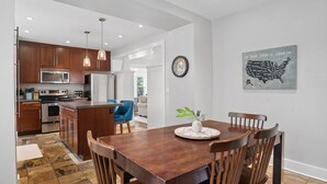 A modern kitchen with wooden cabinets, stainless steel appliances, and a dining area with a wooden table and chairs.