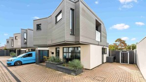 Ein modernes, zweistöckiges Haus mit einem blauen Auto auf der Auffahrt.