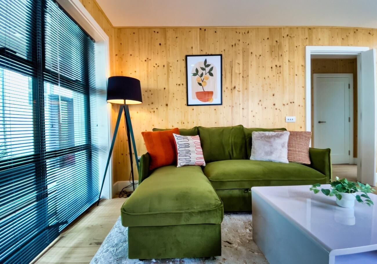 A modern living room with a green sofa set, a white coffee table, and a floor lamp.