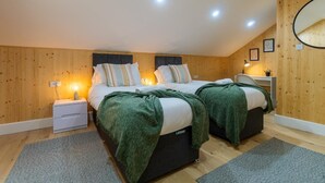 Une chambre avec deux lits, des murs en bois et un luminaire au plafond.