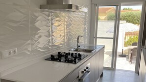 A modern kitchen with a central island, stainless steel appliances, and a view to the outside.