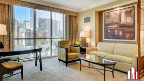 Ein geräumiges Wohnzimmer mit großem Fenster, einer Couch, einem Sessel und einem Couchtisch.
