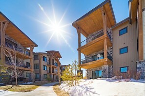 A modern multi-story building with balconies and large windows, surrounded by snow.