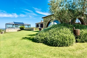 Una casa moderna con facciata in pietra, veranda in vetro e prato curato.