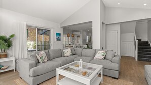 A modern living room with a grey sectional sofa, a white coffee table, and a staircase leading to another level.