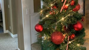 Un sapin de Noël décoré d’ornements rouges et de bâtons de sucre, placé sur une table dans une pièce dotée d’une cheminée et ornée d’un tableau encadré au mur.