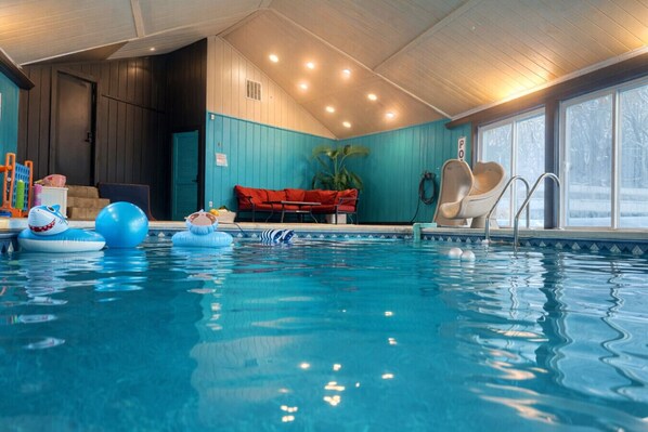 An indoor swimming pool with clear water, a slide, and inflatable toys. - Valley View Villa: Indoor Saltwater pool, theater, pickleball! (Lancaster)