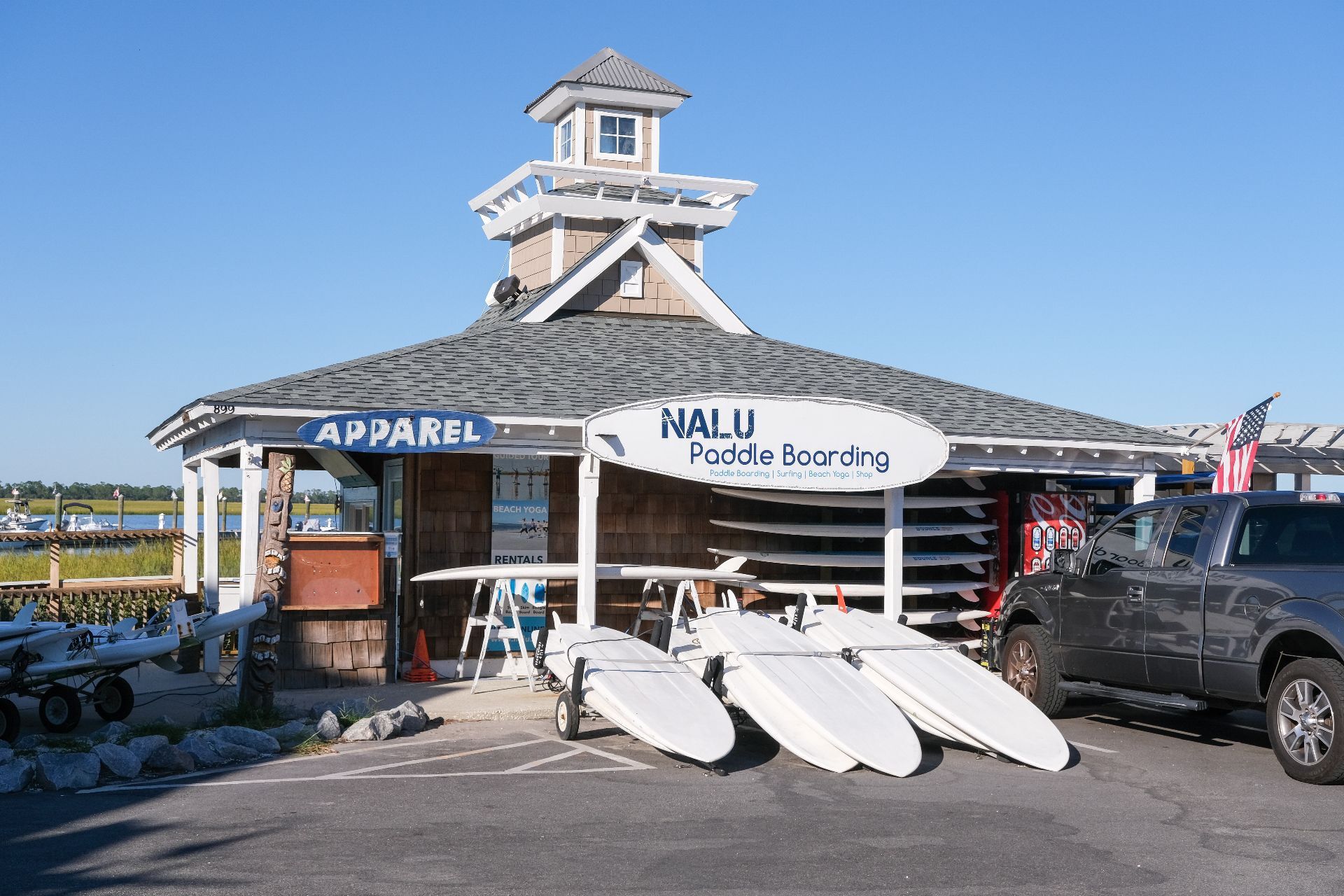 En byggnad med en skylt för NALU Paddle Boarding och en avdelning med kläder och utrustning.