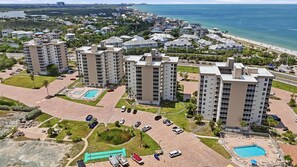 A high-rise residential building complex with multiple balconies, a swimming pool, and a beach view. - Bonita Beach and Tennis Unit 2808 (Bonita Springs)