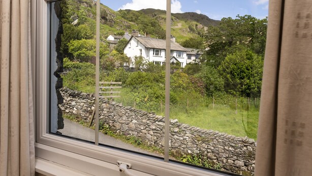 A window with a stone wall and a white house in the background. - Oak Cottage, Chapel Stile (Chapel Stile)