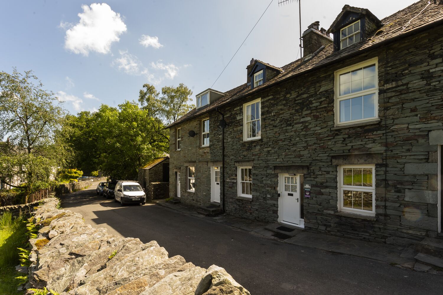 A stone-built row house with a car parked in front.