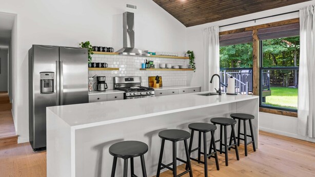 Una cocina moderna con una isla grande, electrodomésticos de acero inoxidable y vistas al exterior.