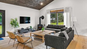 Una sala de estar moderna con chimenea, sofá, televisión y un ventanal grande.