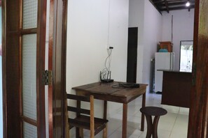 Una cocina pequeña y funcional con una mesa y sillas de madera, un refrigerador y un lavamanos.