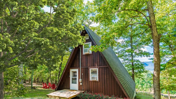 Une cabane en bois avec un toit en pente, une porte d’entrée et un petit porche.