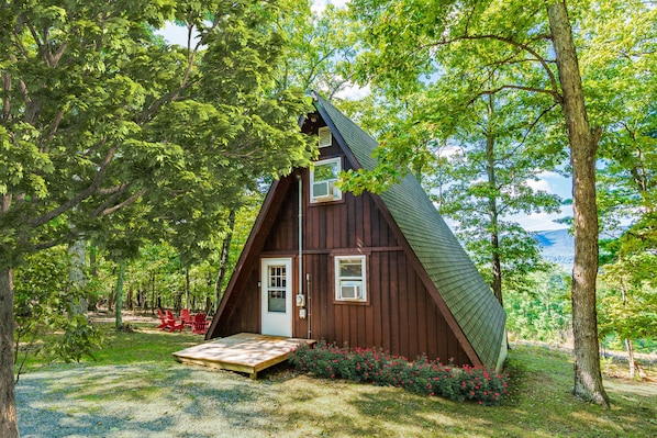 Eine Holzhütte mit geneigtem Dach, einer Haustür und einer kleinen Veranda.