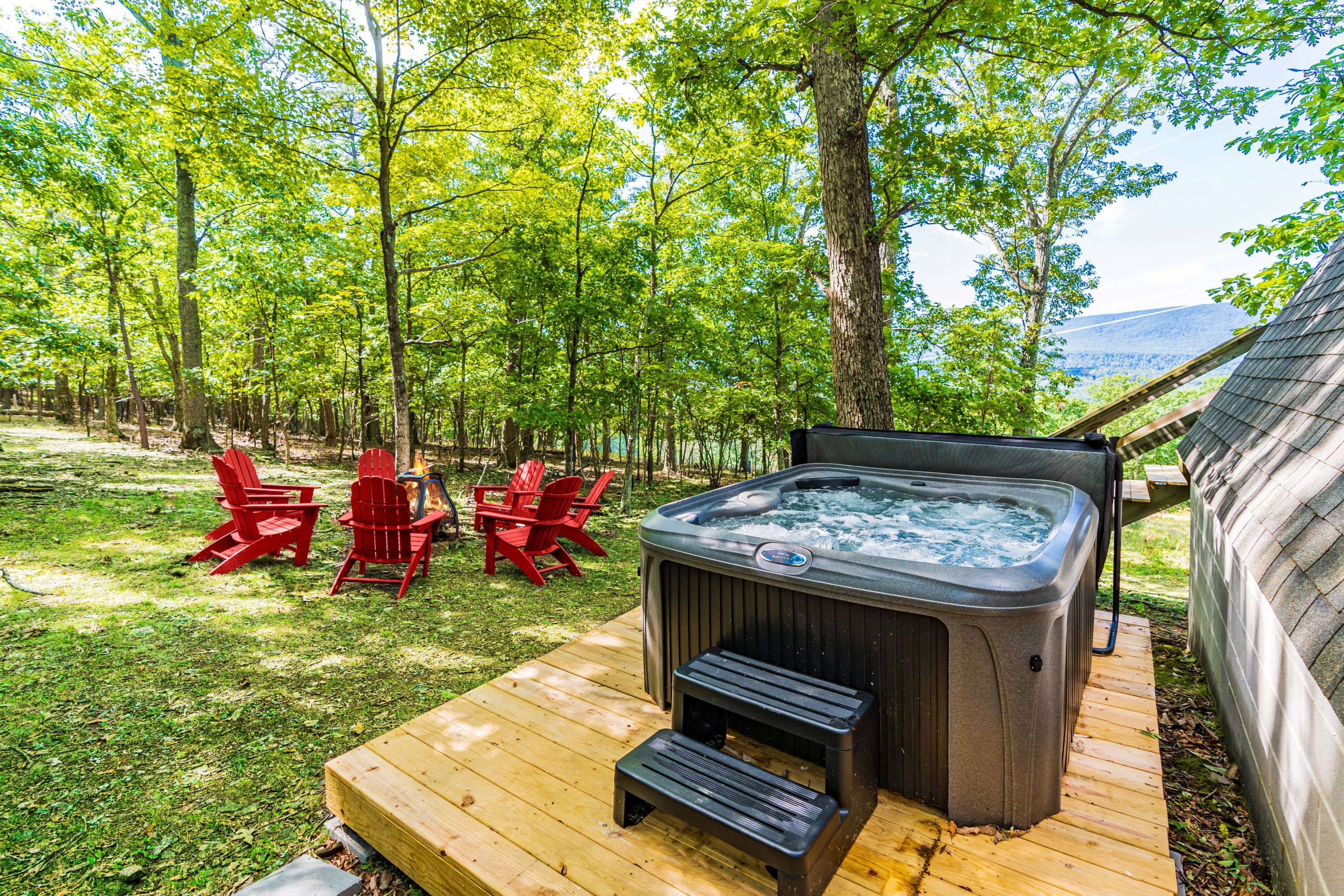 Ein Whirlpool auf einer Holterrasse mit Blick auf einen Wald und Berge.