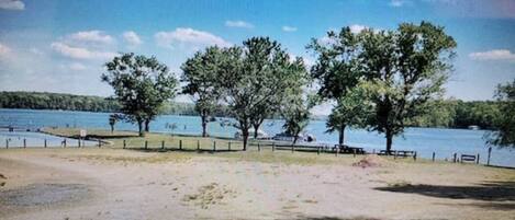 Un parque junto al lago con árboles, bancos y una vista despejada del agua.