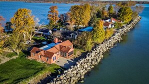 A lakeside property with a stone wall, several houses, and trees.