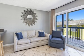 Relax in this stylish living room with a sofa, armchair, and balcony access.