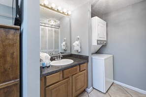 Bathroom features a large mirror, granite countertop, and wooden cabinets.
