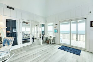 A room with a view of the beach, white walls, a wicker chair, a desk, and a blue rug. - Beachfront w/ Rooftop Deck, Dune Walkover & Nearby to Jamaica Beach Amenities (Jamaica Beach)