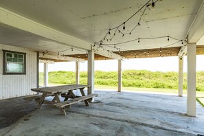 A covered picnic area with a wooden picnic table and benches, concrete floor, and string lights. - Beachfront w/ Rooftop Deck, Dune Walkover & Nearby to Jamaica Beach Amenities (Jamaica Beach)
