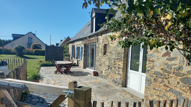 A stone house with a patio, a wooden fence, and a table with chairs. - Single-storey house 100 m from the strikes (Courtils)